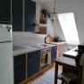 Modern kitchen with blue cupboards, stove, fridge and skylight.