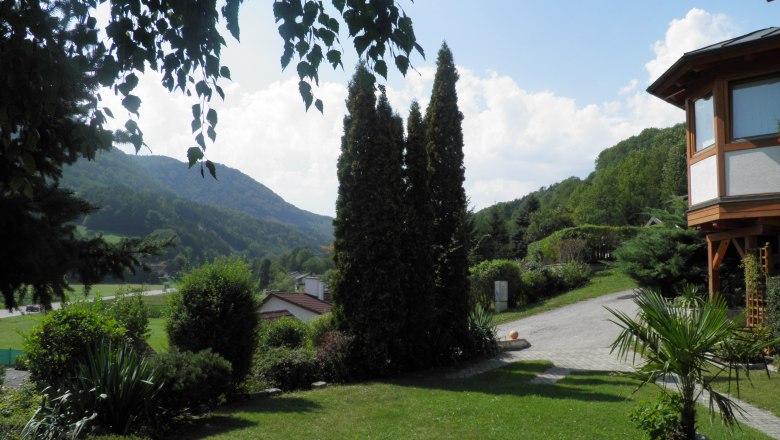 Garden with trees and view of wooded hills in the background.