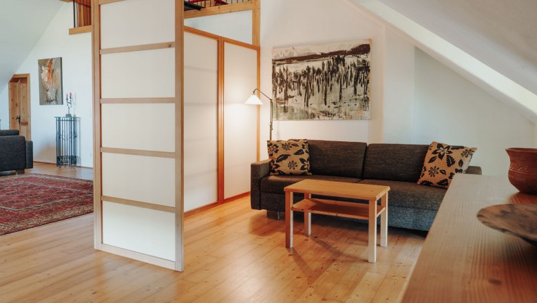 Cozy sitting area with sofa, coffee table and room divider in an attic room.