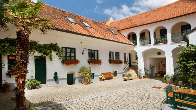 A traditional Austrian courtyard with white buildings, red tiled roofs and flowers.
