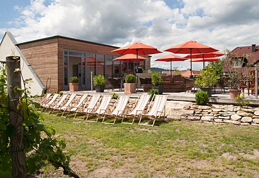 Terrace with sun loungers and red parasols in the garden.