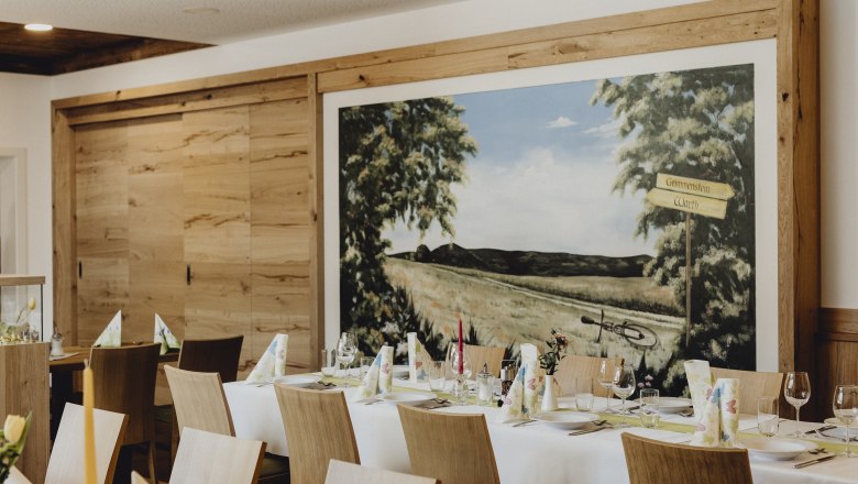 Interior view of an inn with a laid table and wall painting.