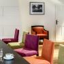 Interior view of a modern hotel lounge with colorful chairs, a table with drinks and a picture on the wall.