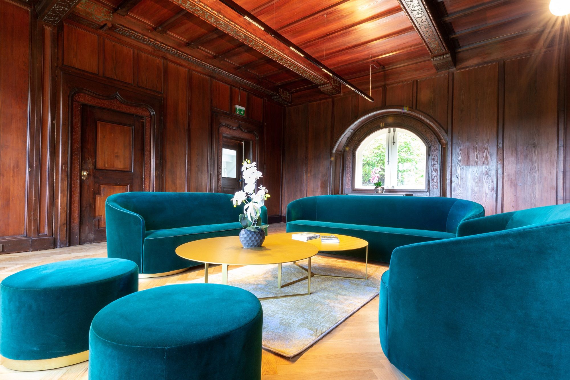 Elegant living room with green sofas and wooden walls.