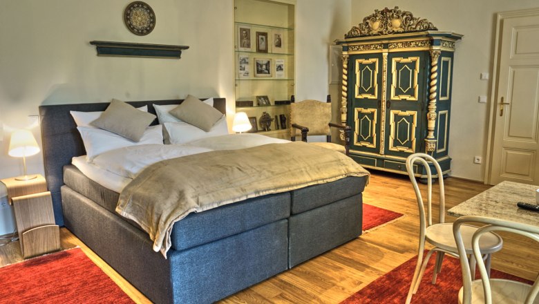 Elegant bedroom with double bed, antique wardrobe and red carpets.
