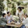 Four people sit at an outdoor table and enjoy wine and bread.