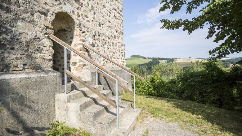 Entrance to the fire tower of the Kirchschlag castle ruins with stairs and landscape in the background.