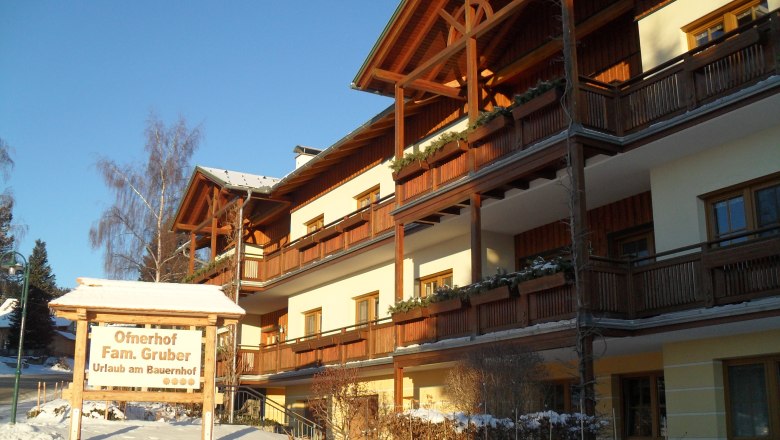 A traditional farmhouse with wooden cladding in winter, labeled 'Ofnerhof Fam. Gruber'.