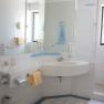 Bright bathroom with washbasin, mirror, shower and towels.