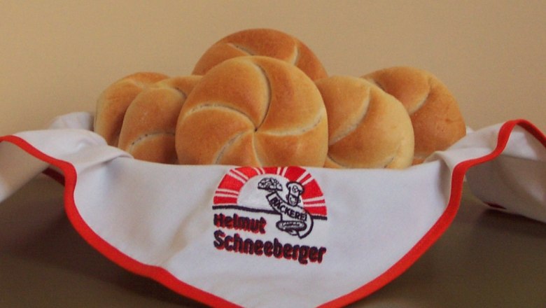 A basket of fresh bread rolls, covered with a napkin from the Helmut Schneeberger bakery.