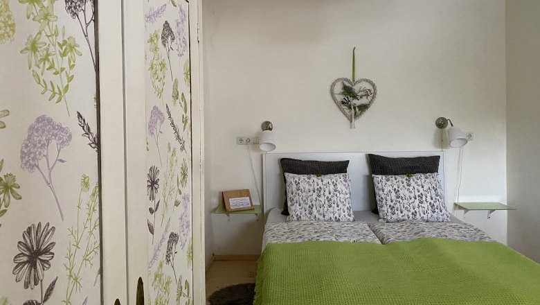 Cozy double room with floral closet and green comforter.