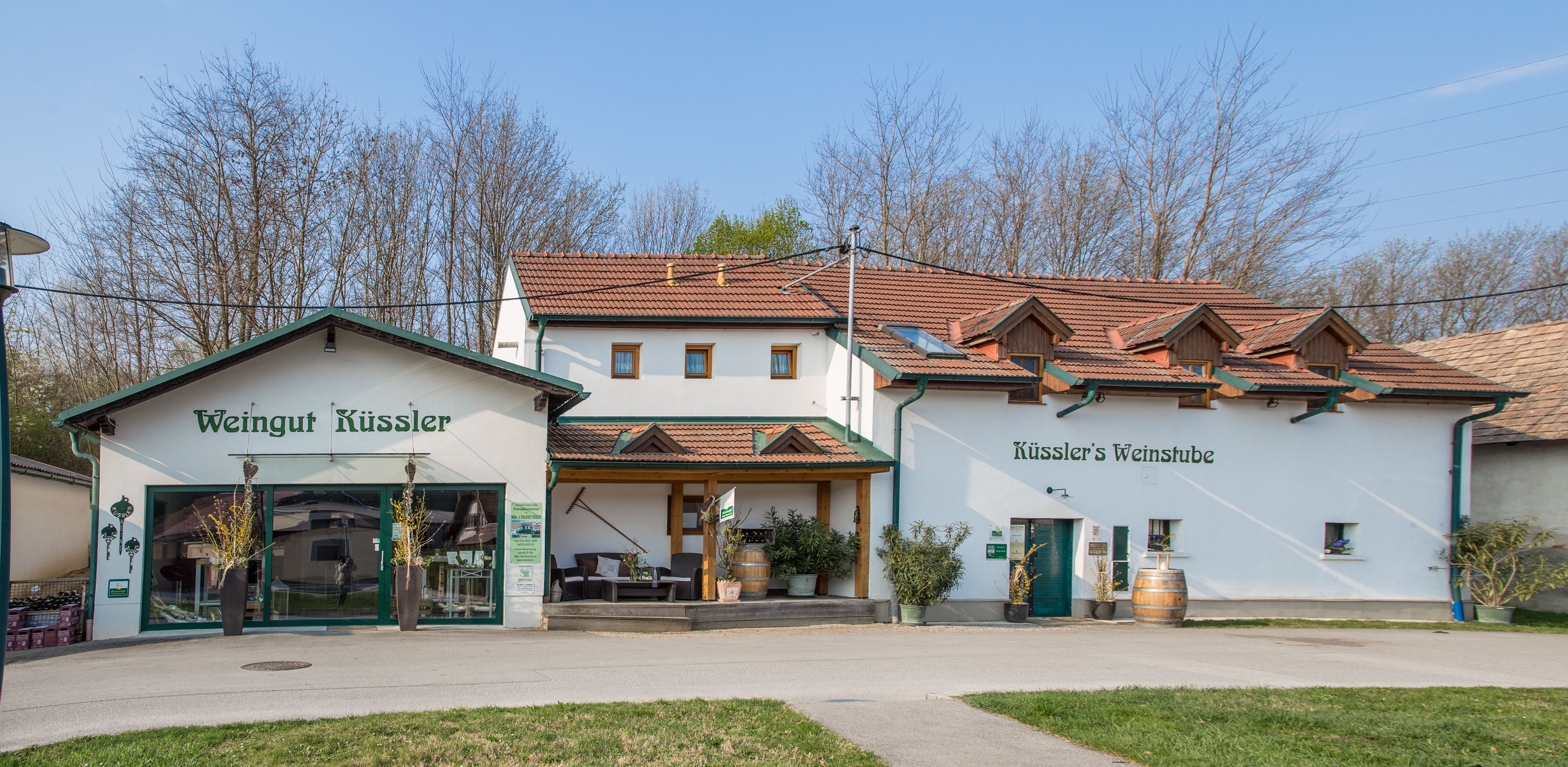 Weingut Küssler with wine bar and terrace, surrounded by trees.