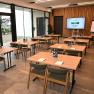 Modern seminar room with wooden tables, chairs and presentation technology.