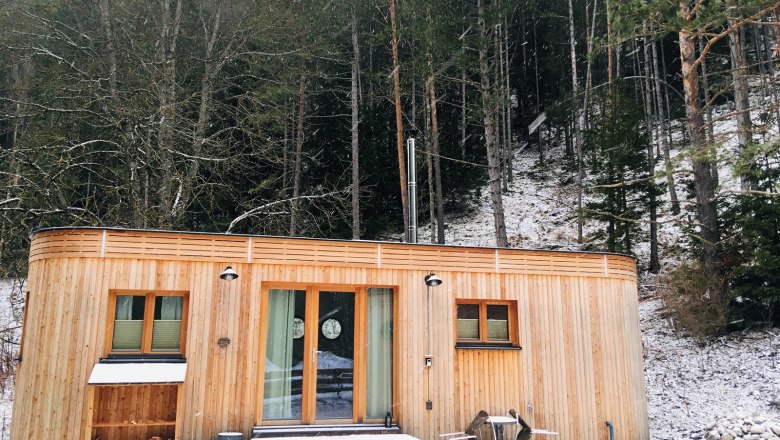 Small wooden house in a winter forest covered in snow.