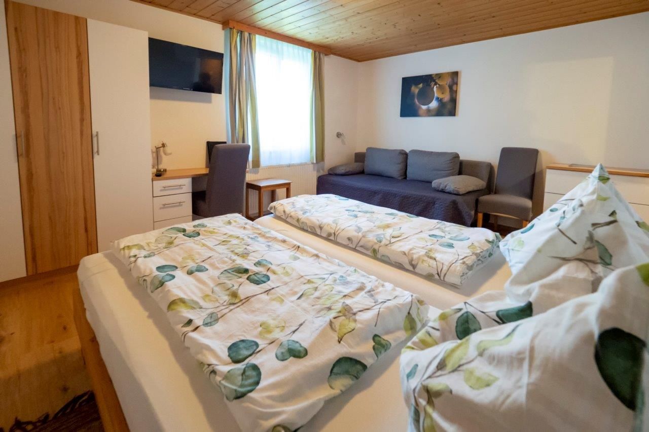 Comfortable guest room with double bed, sofa, desk and TV.