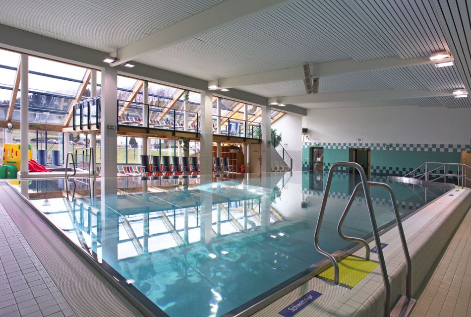 Interior view of a modern indoor pool with large swimming pool and glass front.