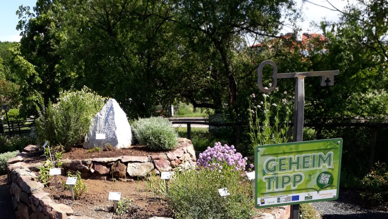 Herb spiral made of stones with plants and a sign with the inscription 'Insider tip'.
