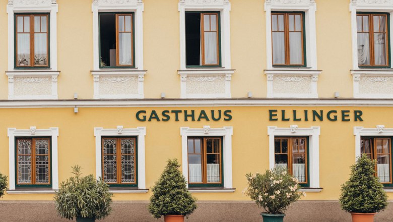 Façade of a yellow inn with the inscription 'Gasthaus Ellinger'.
