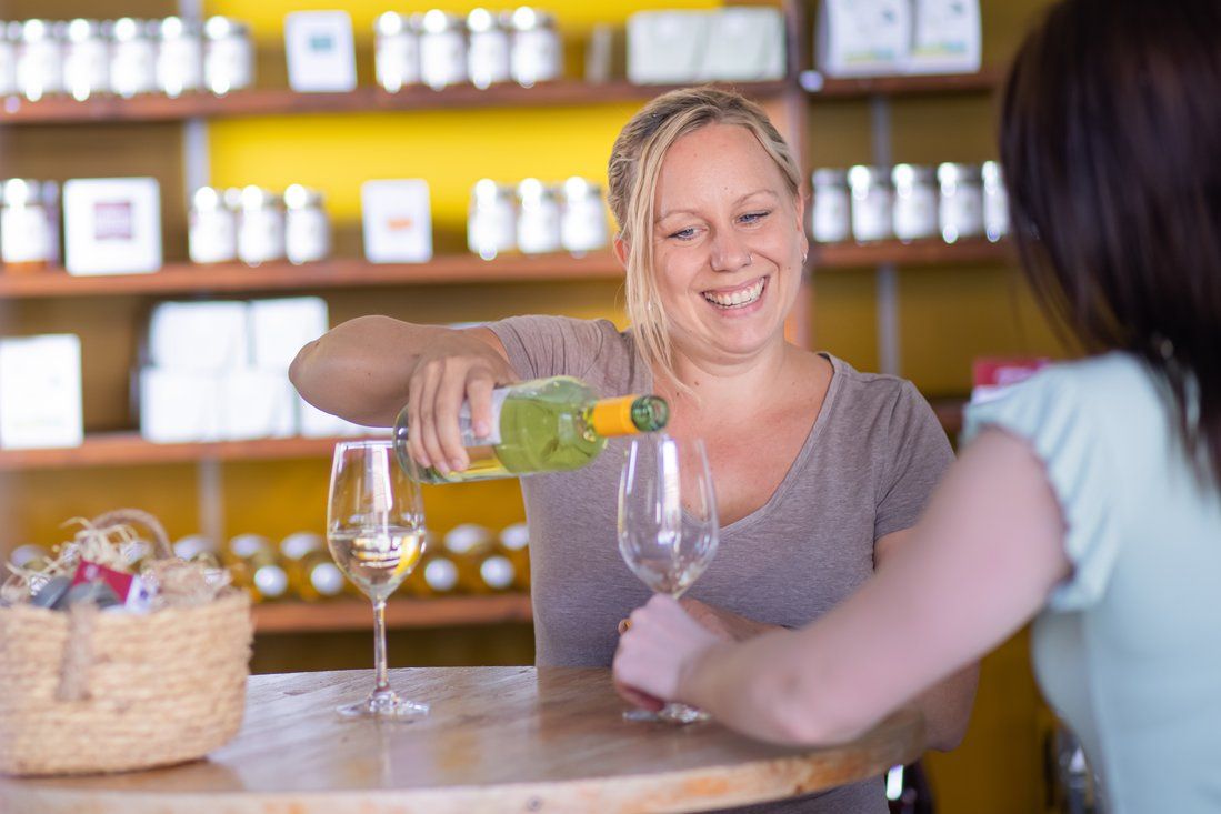 Woman pouring wine into a glass while smiling.