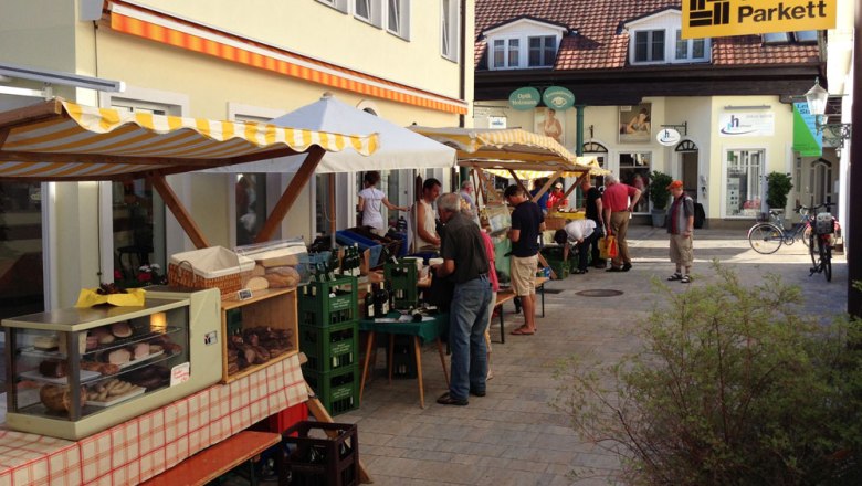 Bauernmarkt in einer Passage mit Ständen und Besuchern.