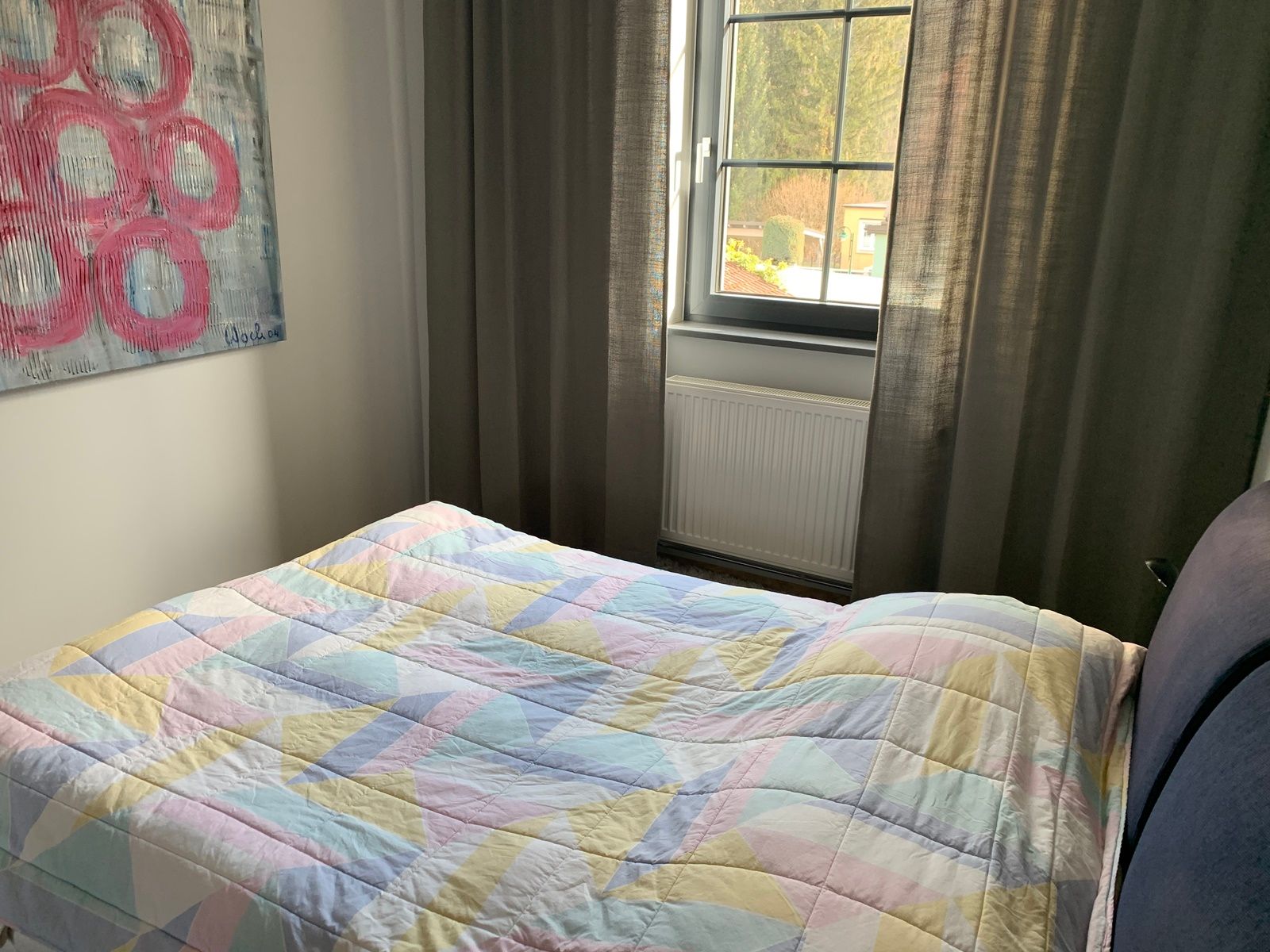 Bedroom with bed, colorful ceiling, window and artwork on the wall.