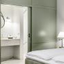 Hotel room with green sliding-door wardrobe, bed and view of the bathroom.