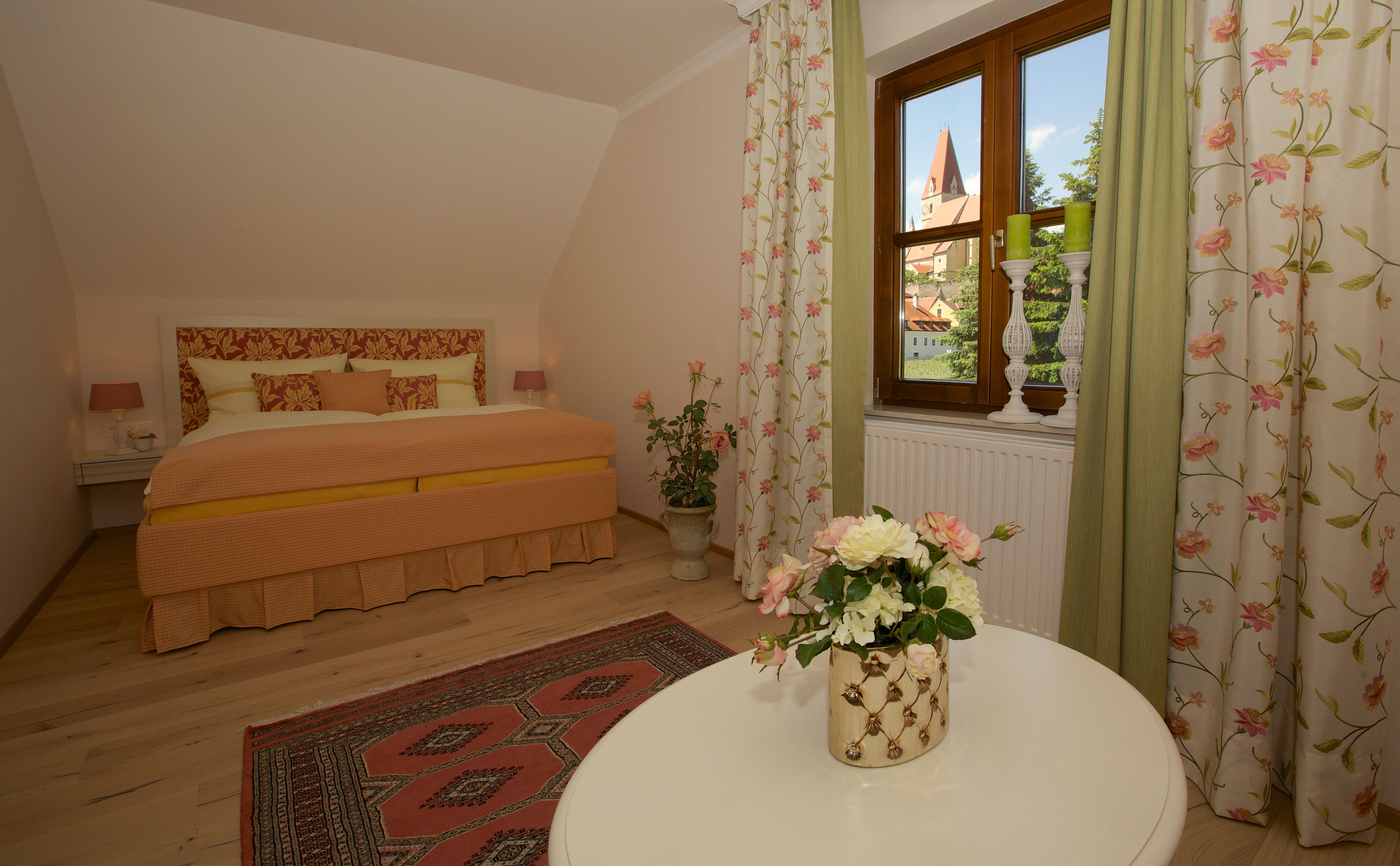 Cozy bedroom with floral design and view of a church through the window.