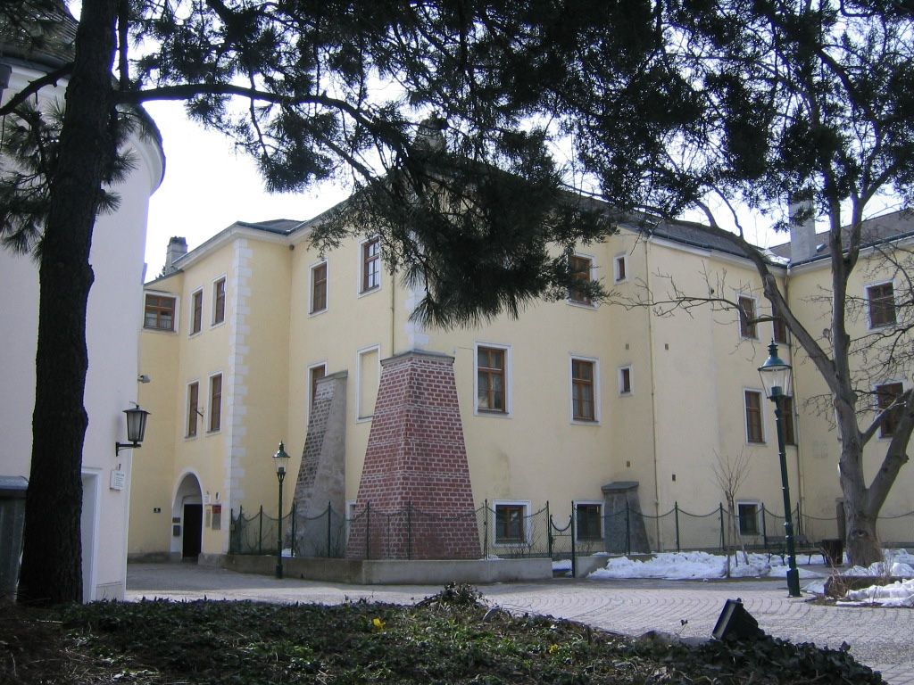 Purkersdorf Castle in winter with snow-covered ground and trees in the foreground.