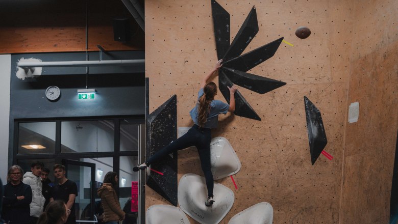 A woman climbs on an indoor climbing wall with black and white holds.