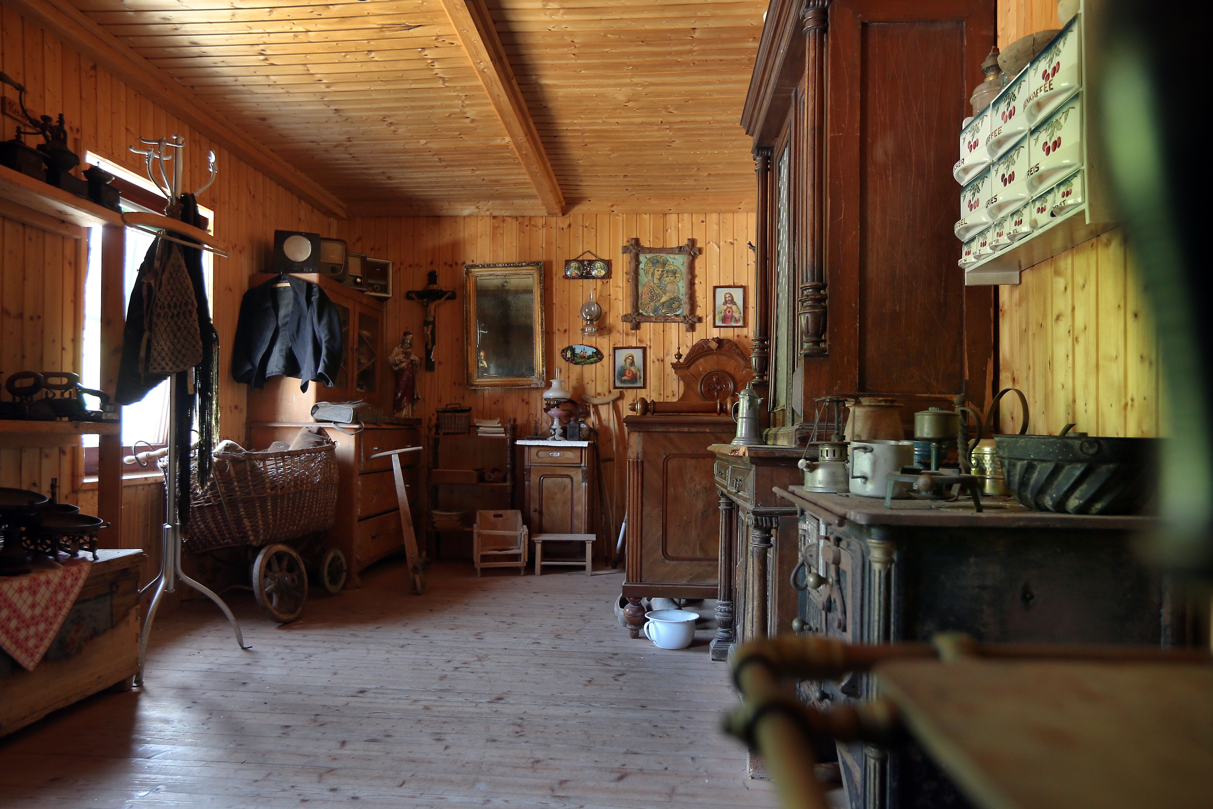 Interior view of a traditional mountain farmhouse with wooden furniture and antique objects.
