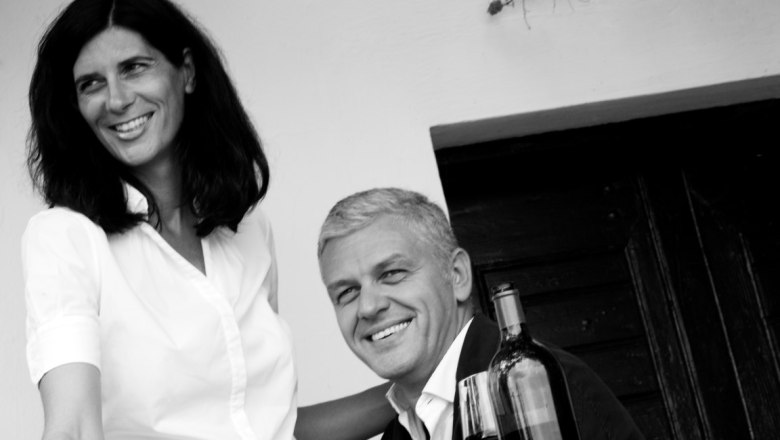 Black and white photo of a smiling couple with a bottle of wine.