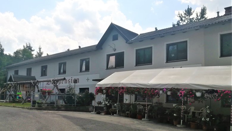 A two-storey building with the inscription 'Waldpension', surrounded by flowers and a canopy.