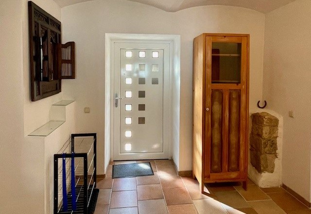 Entrance area with white door, wooden cupboard and tiled floor.