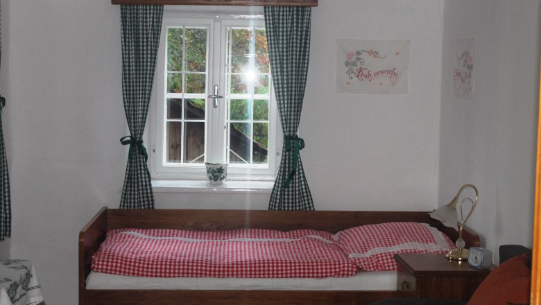 Cozy bedroom with single bed, checkered bedding and green and white checkered curtains.