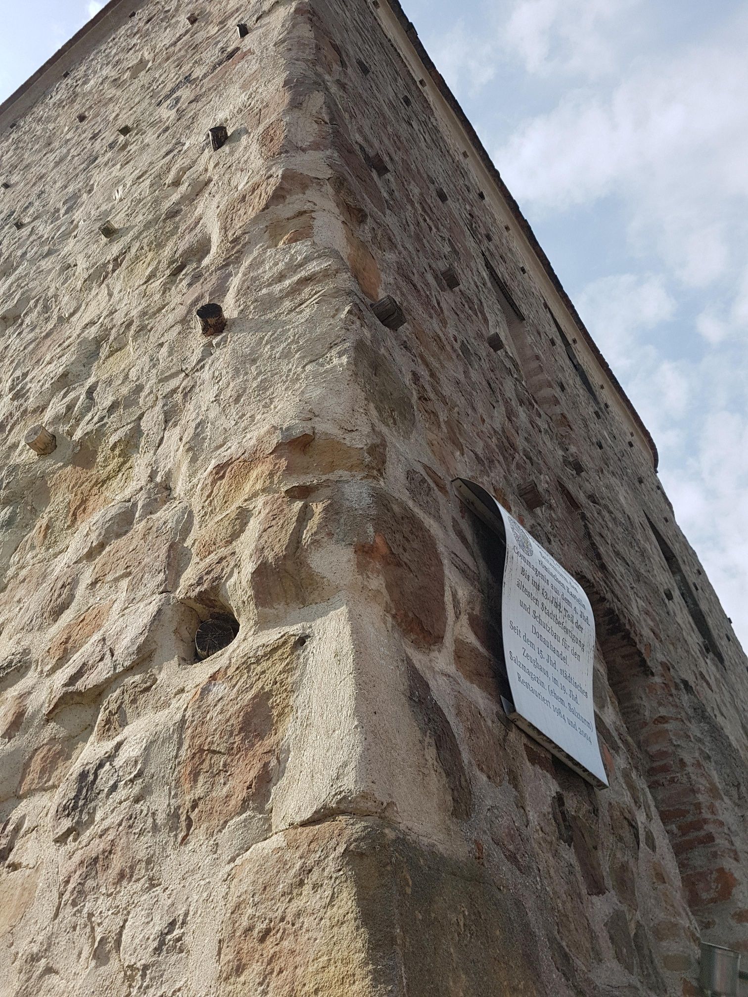 Close-up of an old stone tower with an information board on the wall.
