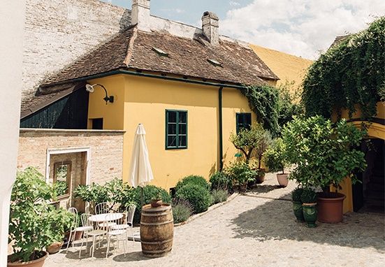 A picturesque courtyard with a yellow house, plants and seating area.