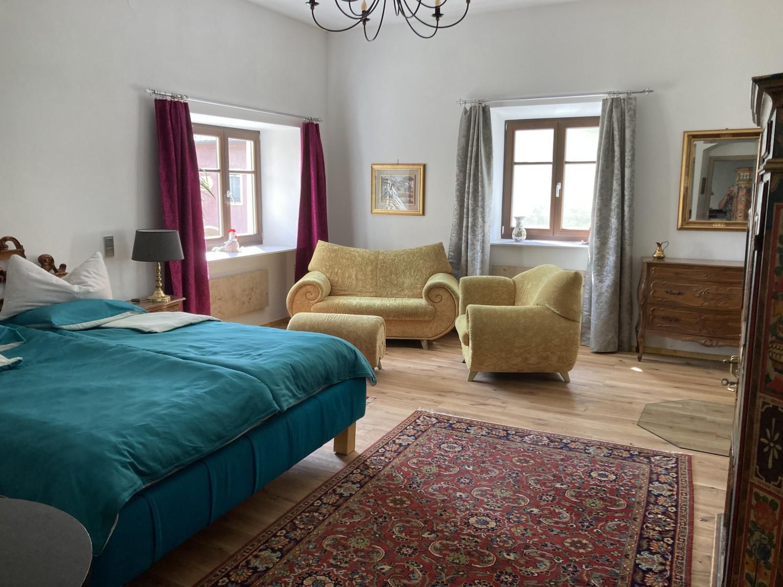 Cozy bedroom with blue bed, yellow armchairs, carpet and wooden furniture.