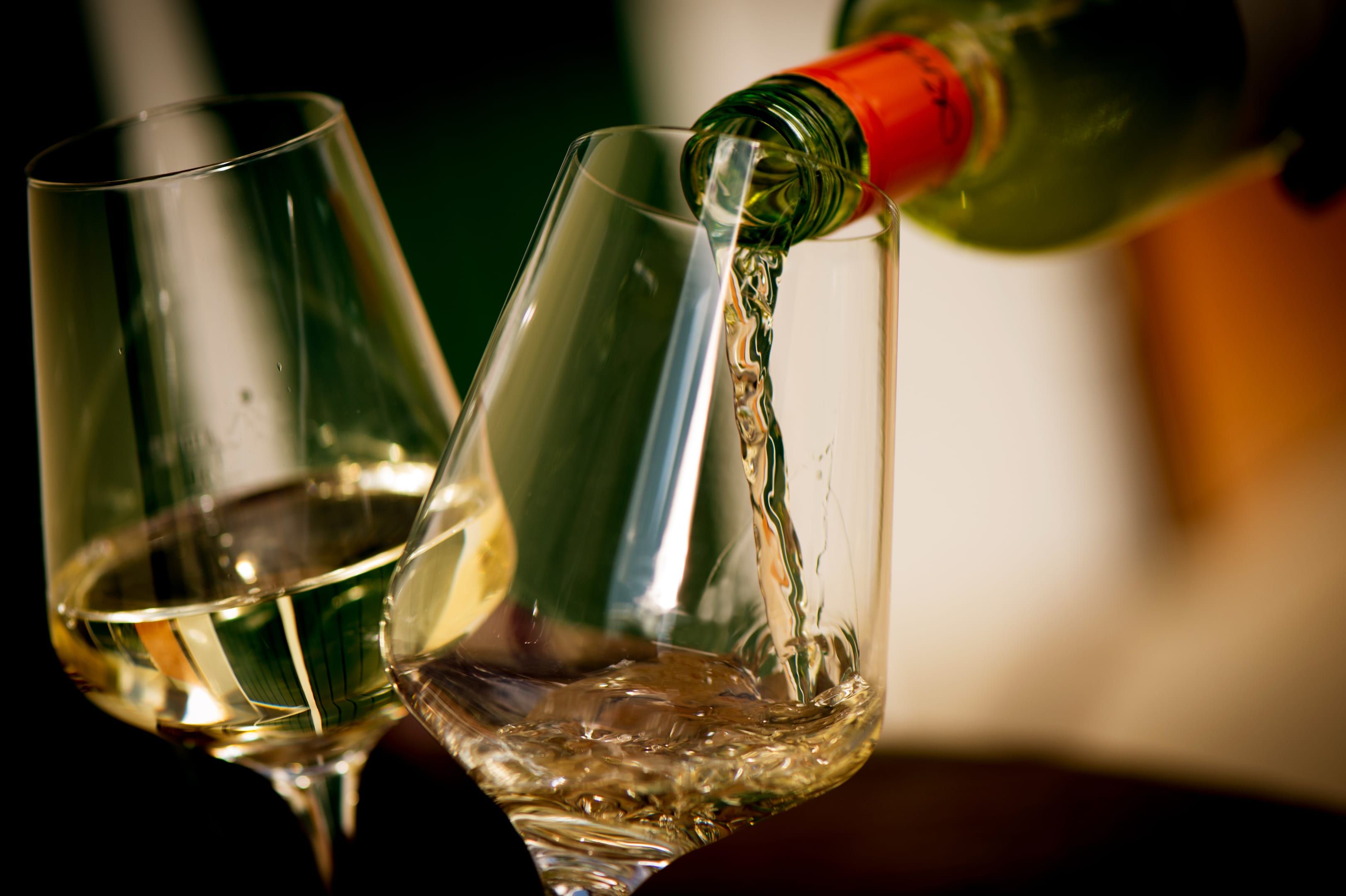 White wine is poured into a glass, with another filled glass next to it.
