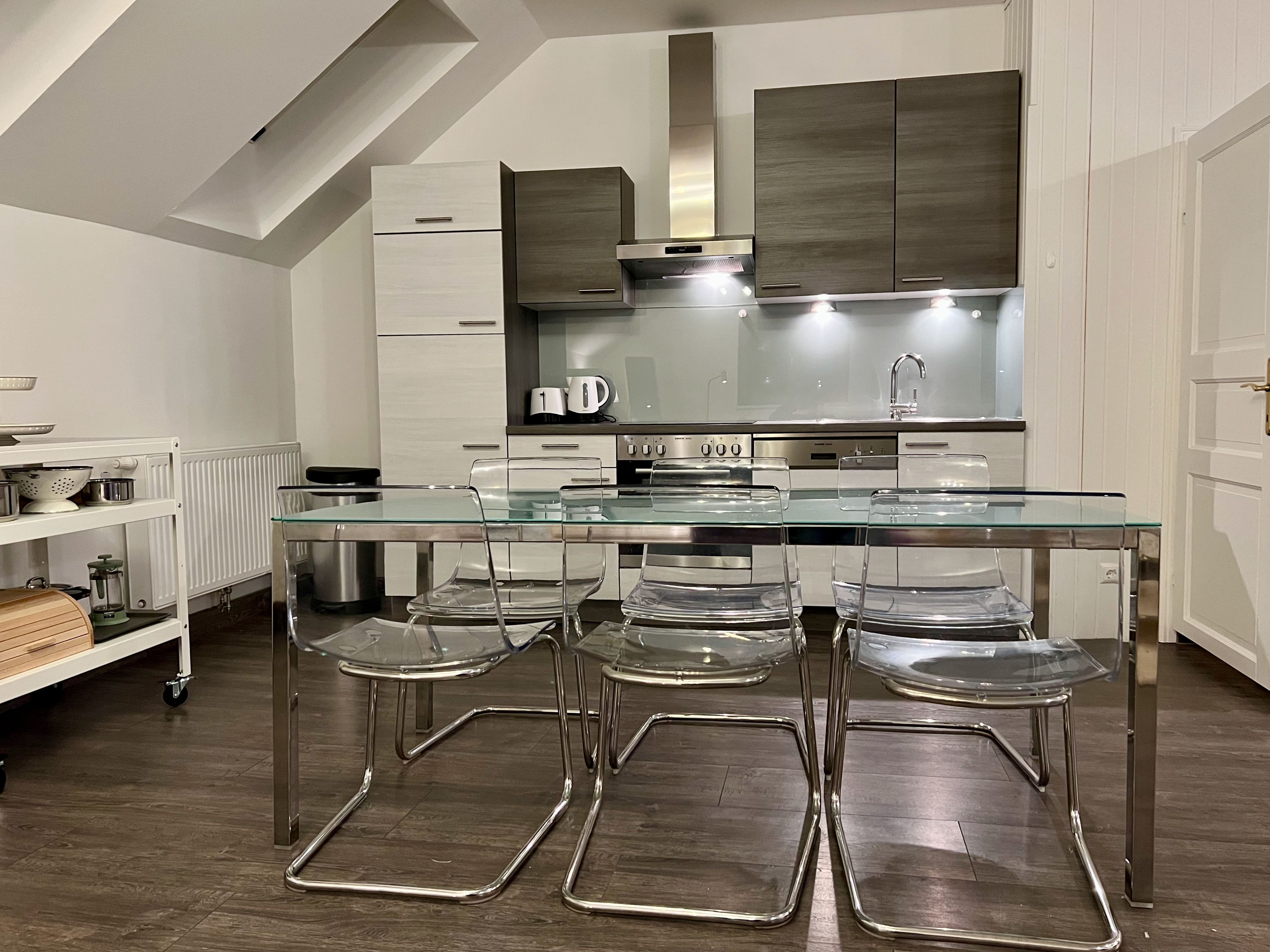 Modern kitchen with glass dining table and transparent chairs in a loft.