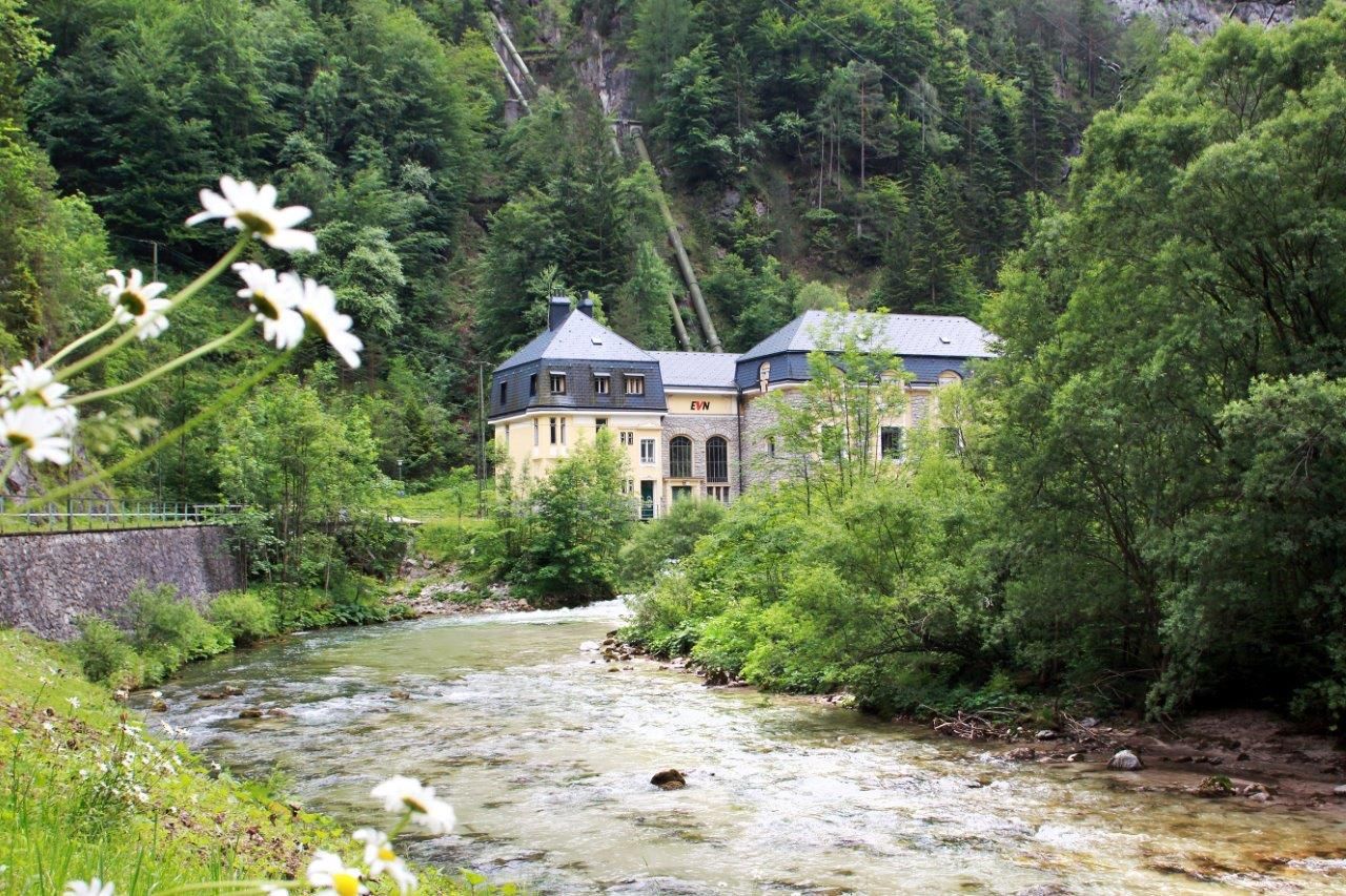 EVN's Wienerbruck power plant in a green landscape with a river.