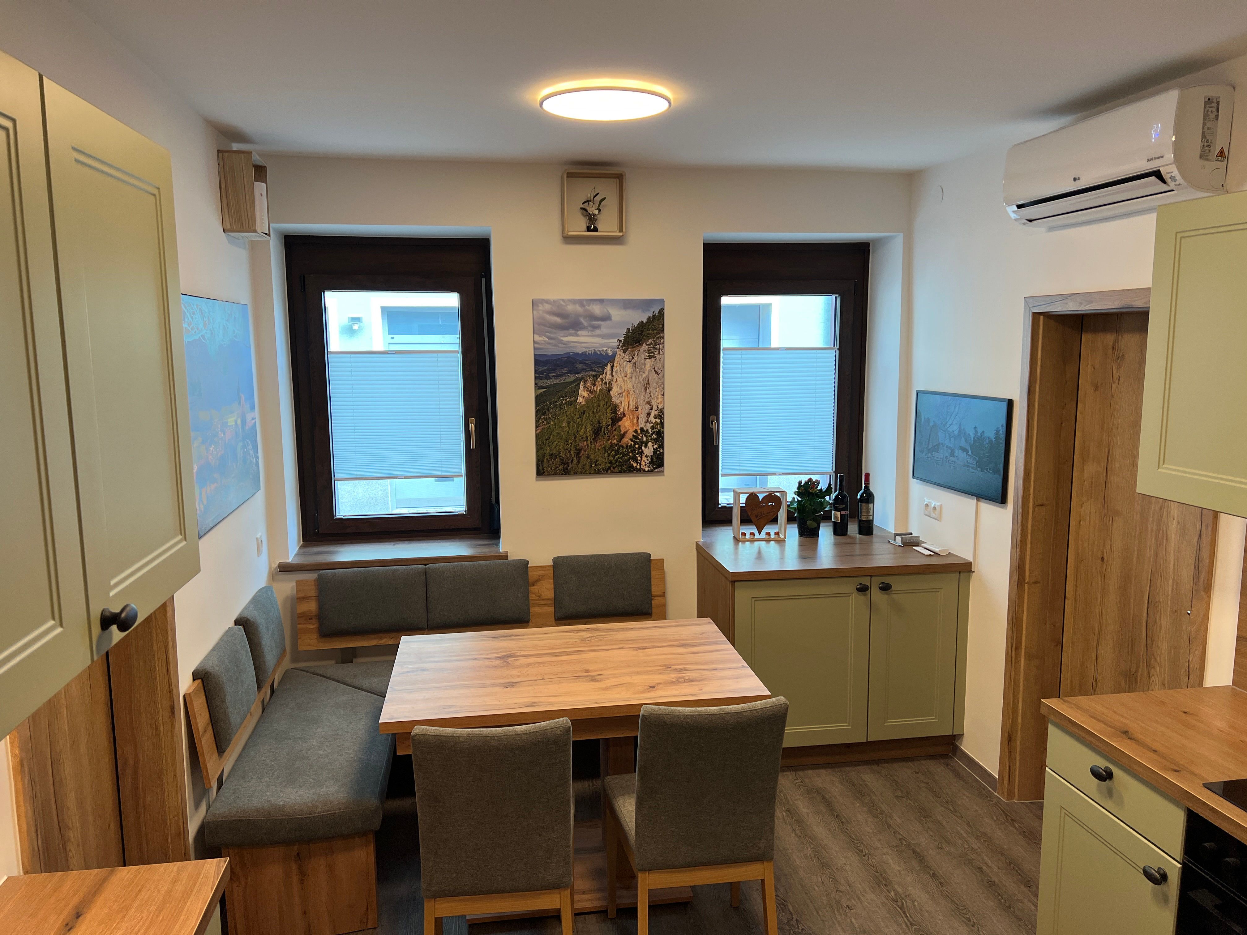 Modern kitchen with wooden furniture, dining table and green cupboards.