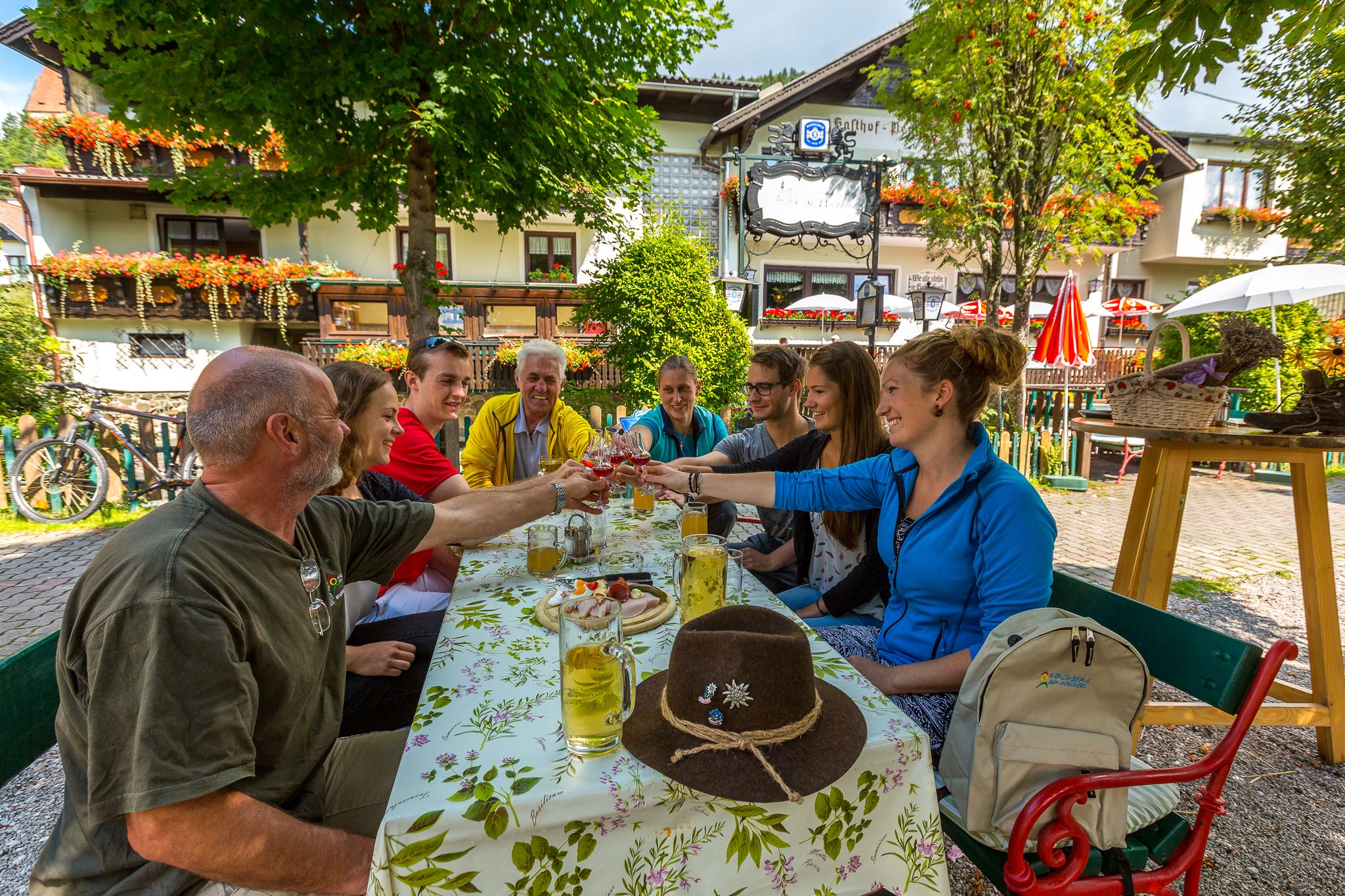 Group of people clinking glasses in a restaurant garden.
