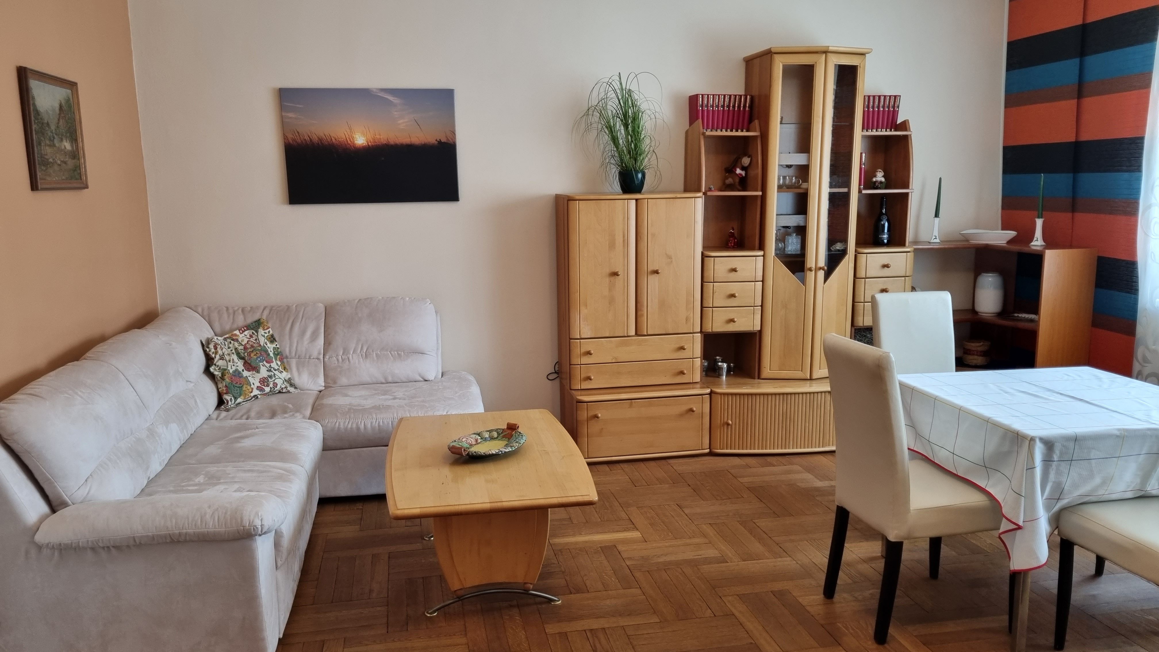 Living room with beige couch, wooden furniture and dining table.