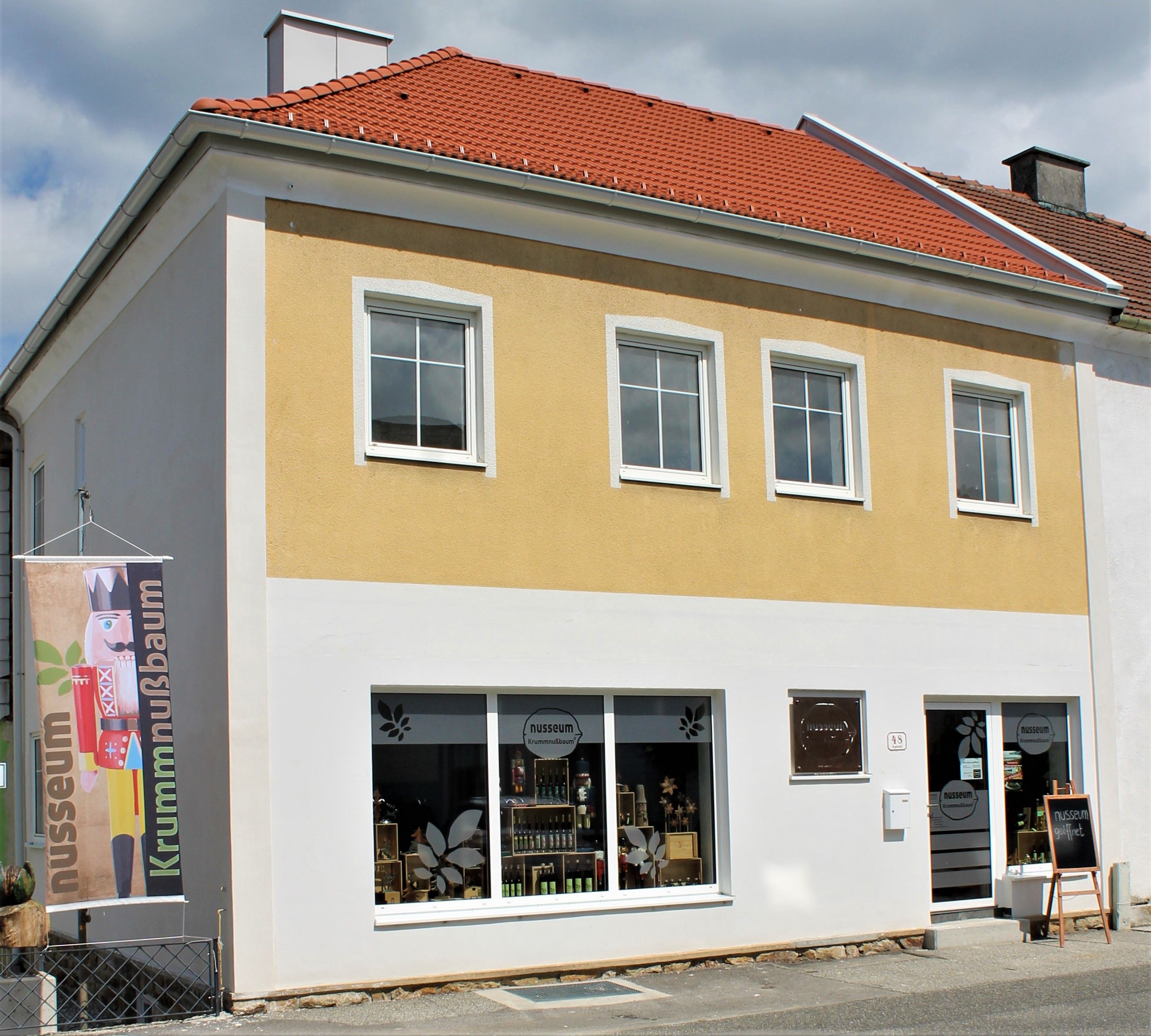 Exterior view of the Nusseum in Krummnussbaum with yellow façade and shop windows.