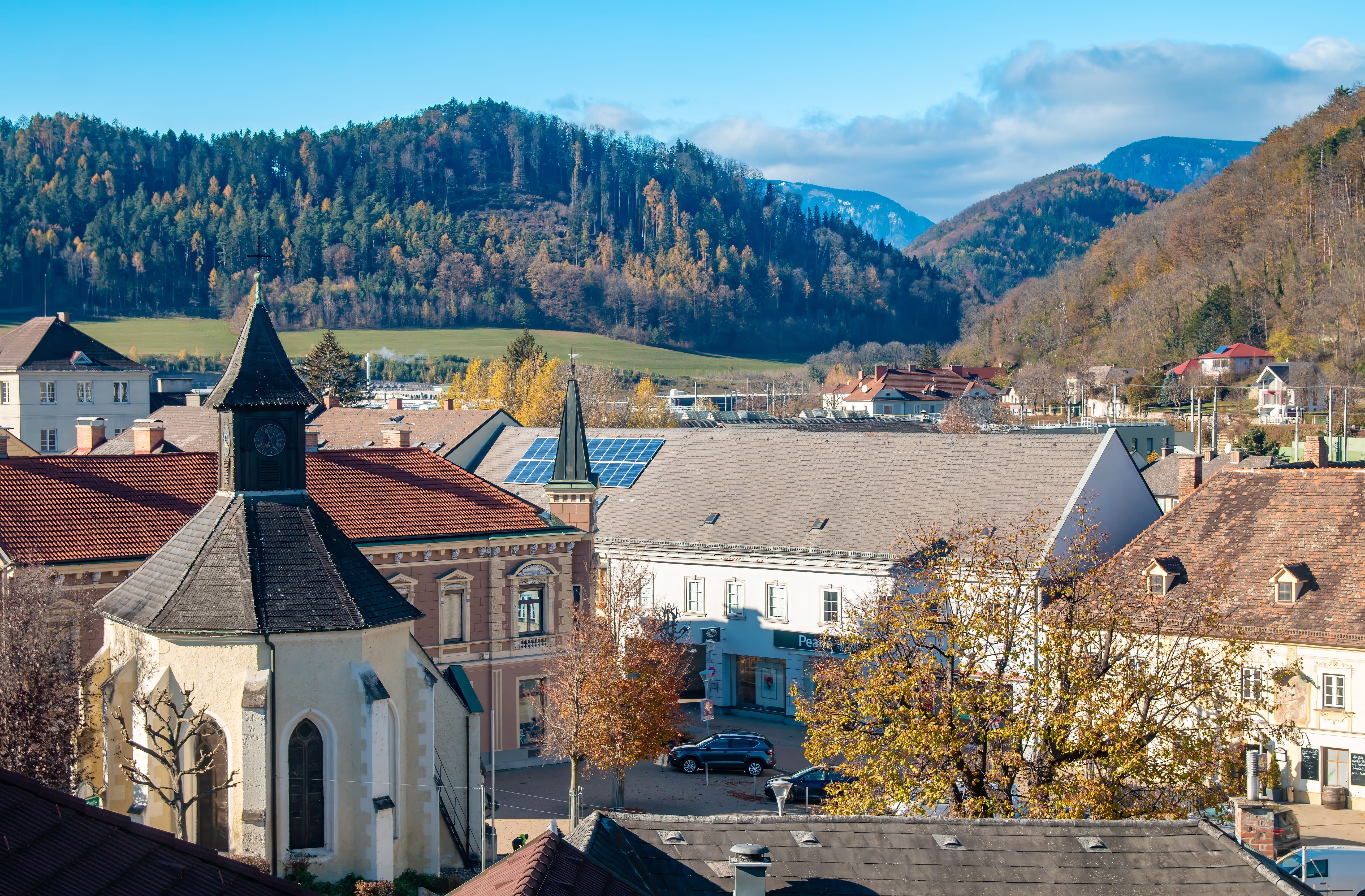 Town view of Gloggnitz with chapel, buildings and wooded hills in the background.
