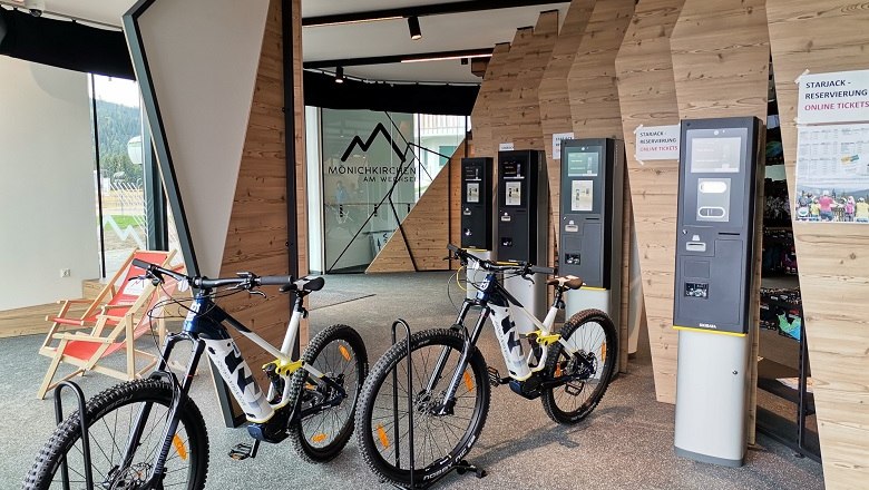 Interior view of an e-MTB rental shop with bikes and ticket machines.