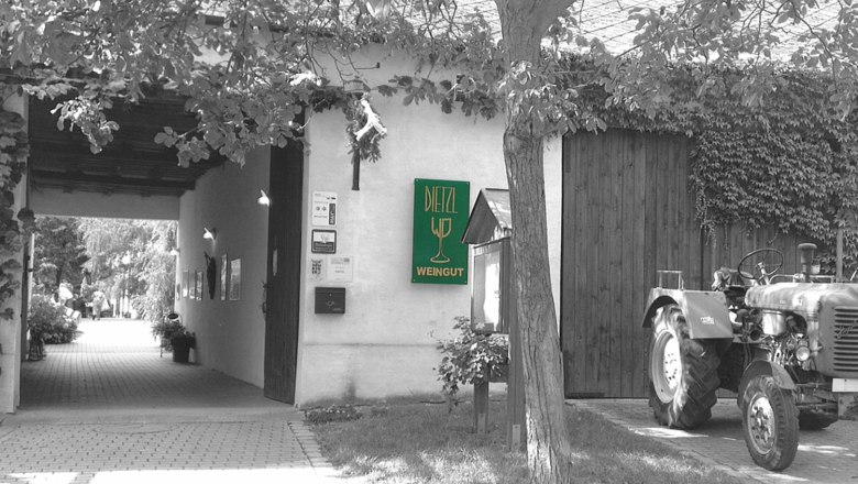 Entrance of a winery with a sign 'Dietzl Weingut' and a tractor next to it.