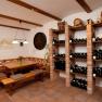 A wine cellar with a table and benches for tasting, surrounded by wine racks full of bottles.