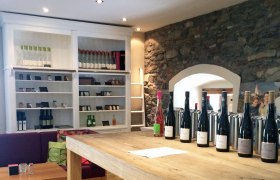 Tasting room with wine bottles on a wooden table and shelves in the background.