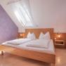 Bright bedroom with skylight, purple wall and wooden bed.